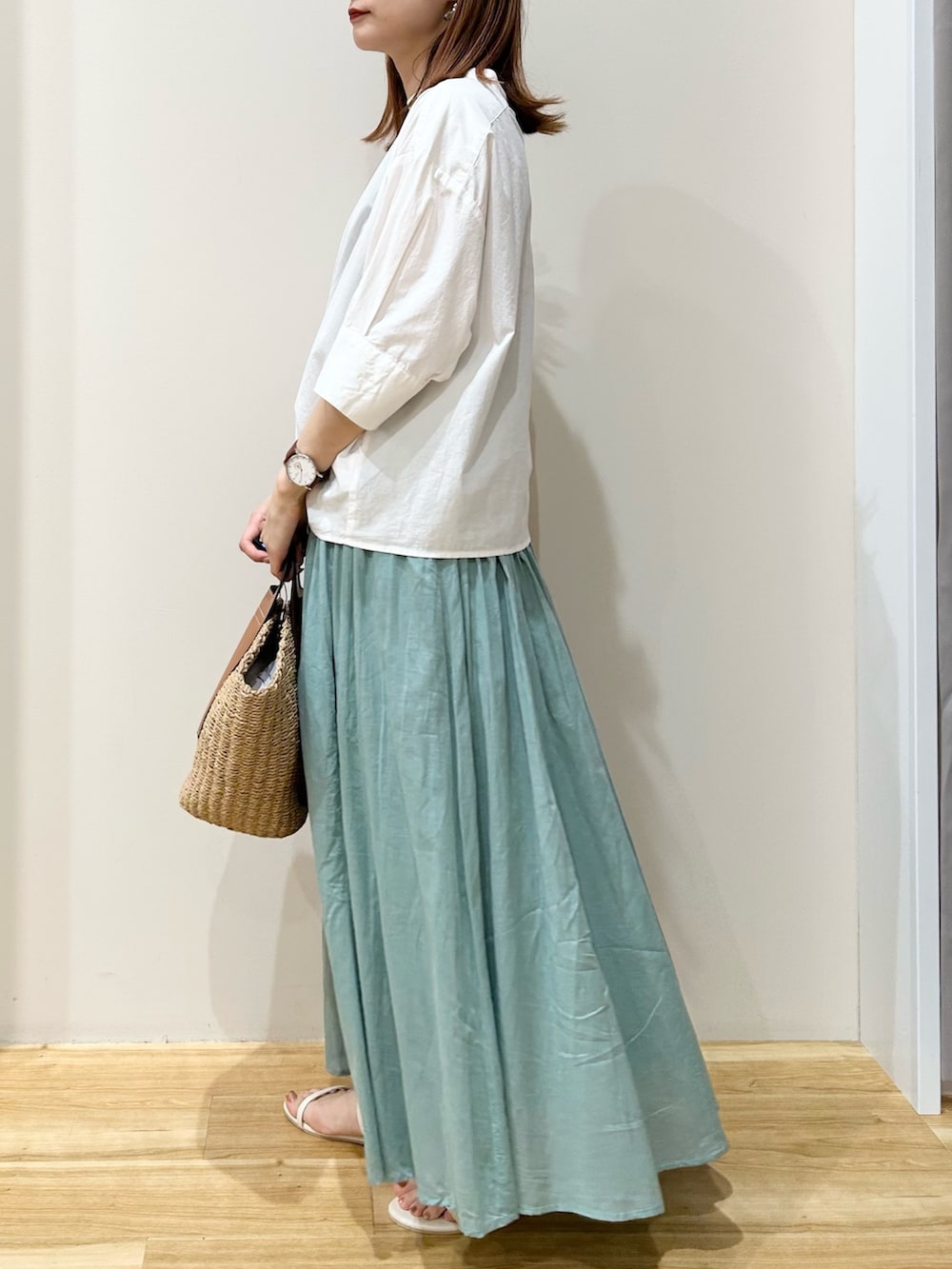 ホワイト系のサンダル、ベージュ系のトートバッグ、グリーン系のスカートを着用したレディースの夏コーディネートの2枚目の写真