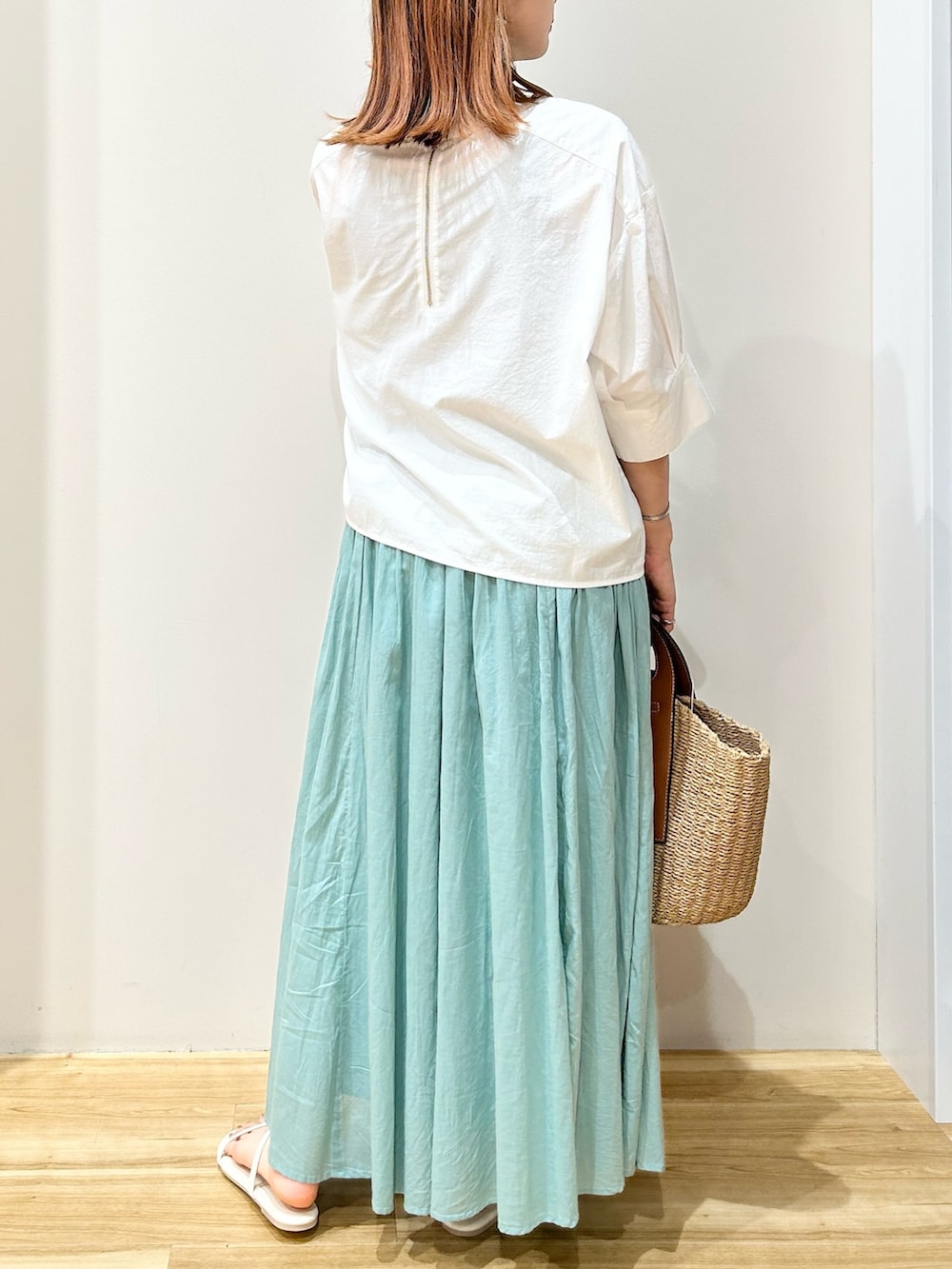 ホワイト系のサンダル、ベージュ系のトートバッグ、グリーン系のスカートを着用したレディースの夏コーディネートの3枚目の写真