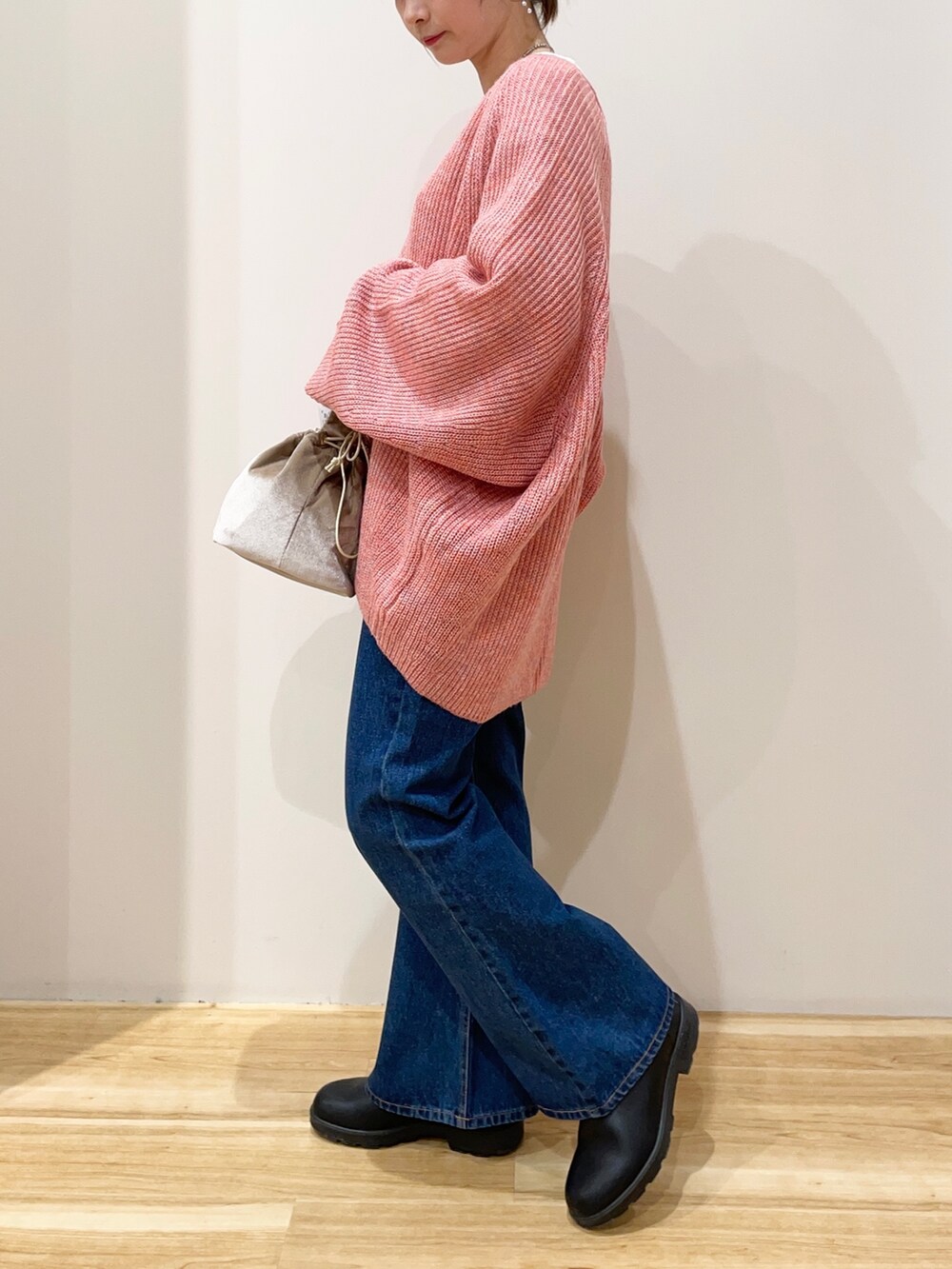 ホワイト系のTシャツ/カットソー、オレンジ系のニット/セーター、ベージュ系のショルダーバッグを着用したレディースの春コーディネートの3枚目の写真