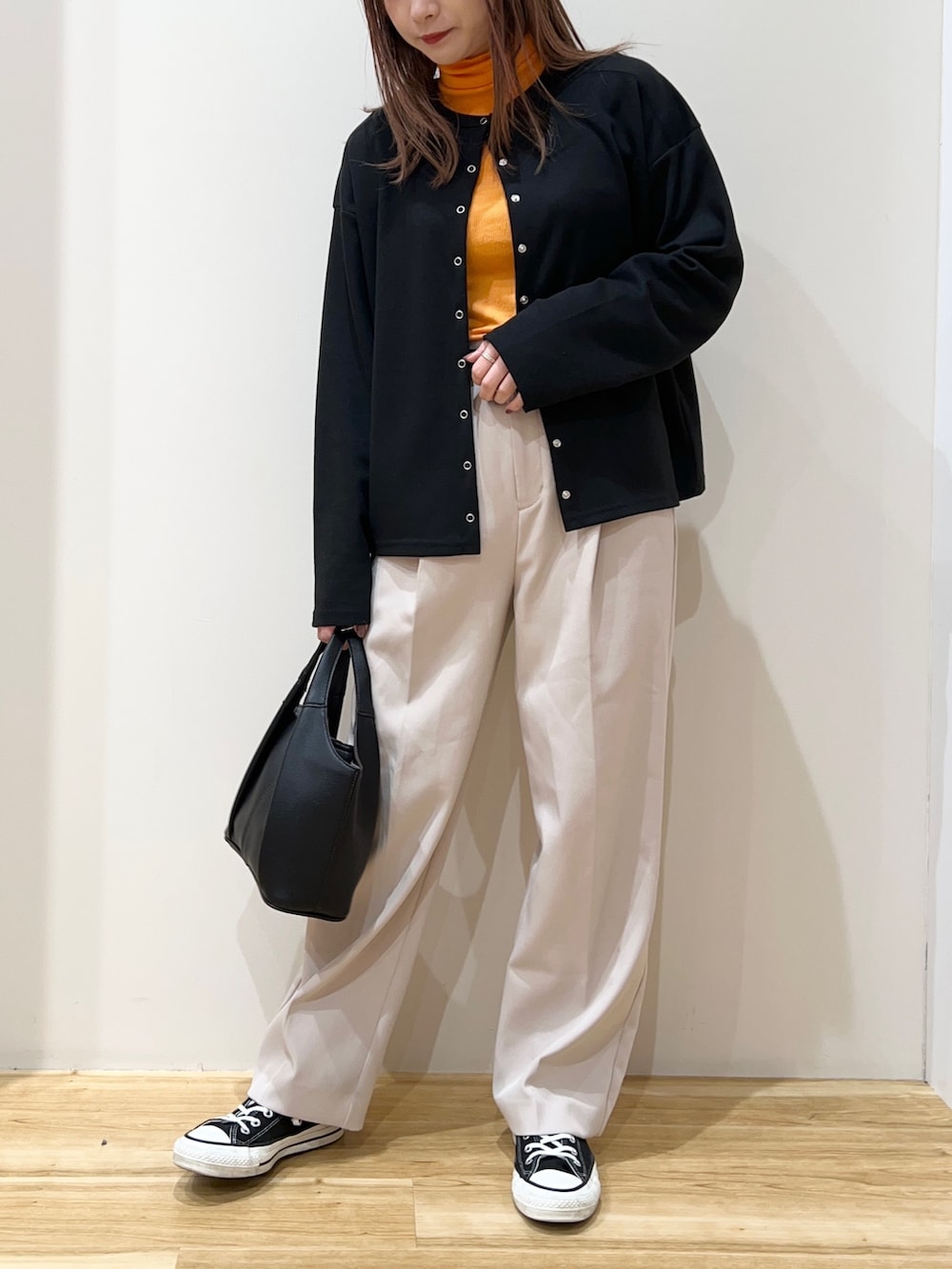 ブラック系のカーディガン/ボレロ、オレンジ系のTシャツ/カットソー、ベージュ系のその他パンツを着用したレディースの春コーディネートの3枚目の写真