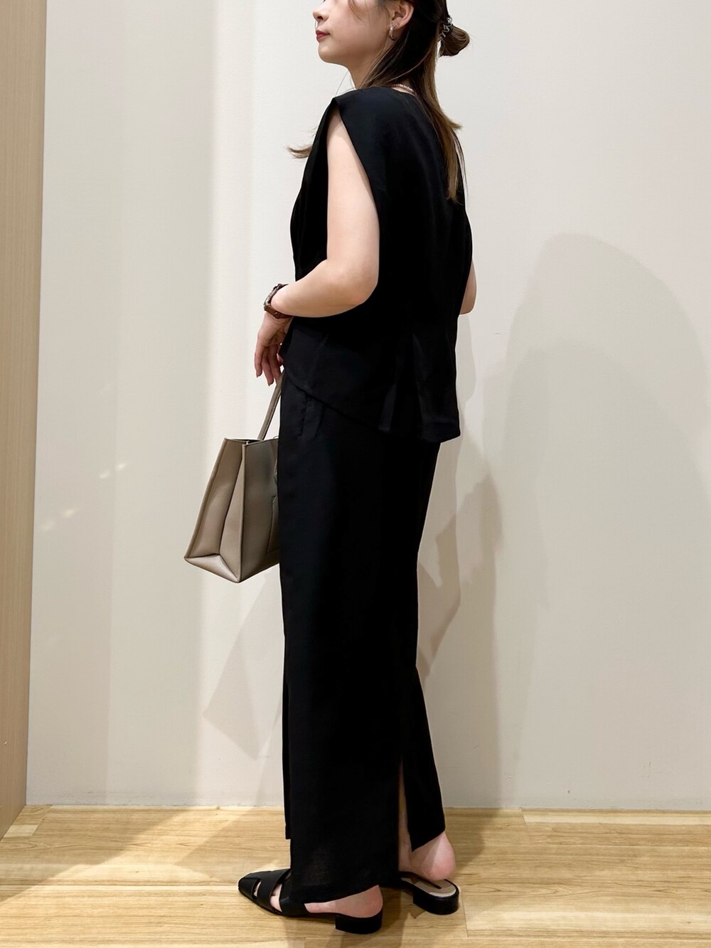 グレー系のトートバッグ、ブラック系のサンダル、ブラック系のワンピースを着用したレディースの夏コーディネートの2枚目の写真