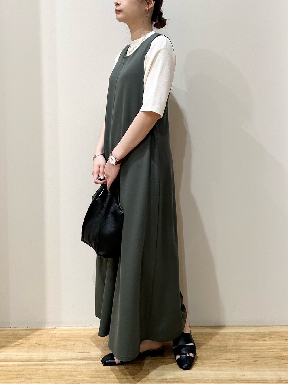 ホワイト系のニット/セーター、グリーン系のジャンパースカート、ブラック系のトートバッグを着用したレディースの春コーディネートの2枚目の写真