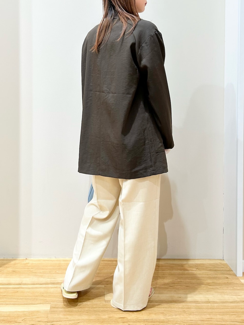 ブラウン系のテーラードジャケット、ブルー系のハンドバッグ、グリーン系のサンダルを着用したレディースの春コーディネートの3枚目の写真