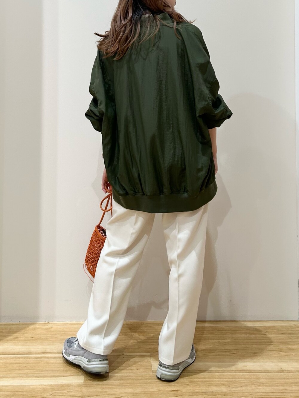 グリーン系のブルゾン、ホワイト系のニット/セーター、ホワイト系のスラックスを着用したレディースの春コーディネートの3枚目の写真