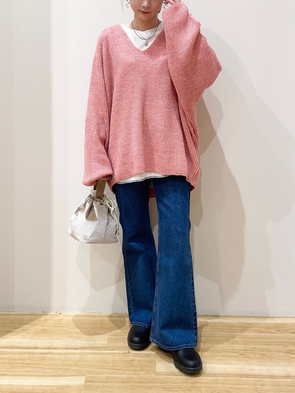 ホワイト系のTシャツ/カットソー、オレンジ系のニット/セーター、ベージュ系のショルダーバッグを着用したレディースの春コーディネートの2枚目の写真