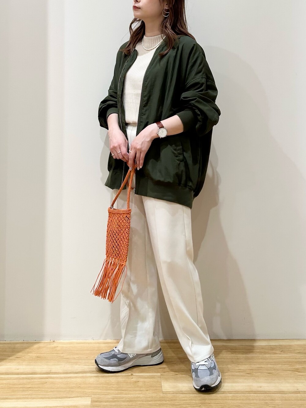 グリーン系のブルゾン、ホワイト系のニット/セーター、ホワイト系のスラックスを着用したレディースの春コーディネートの4枚目の写真