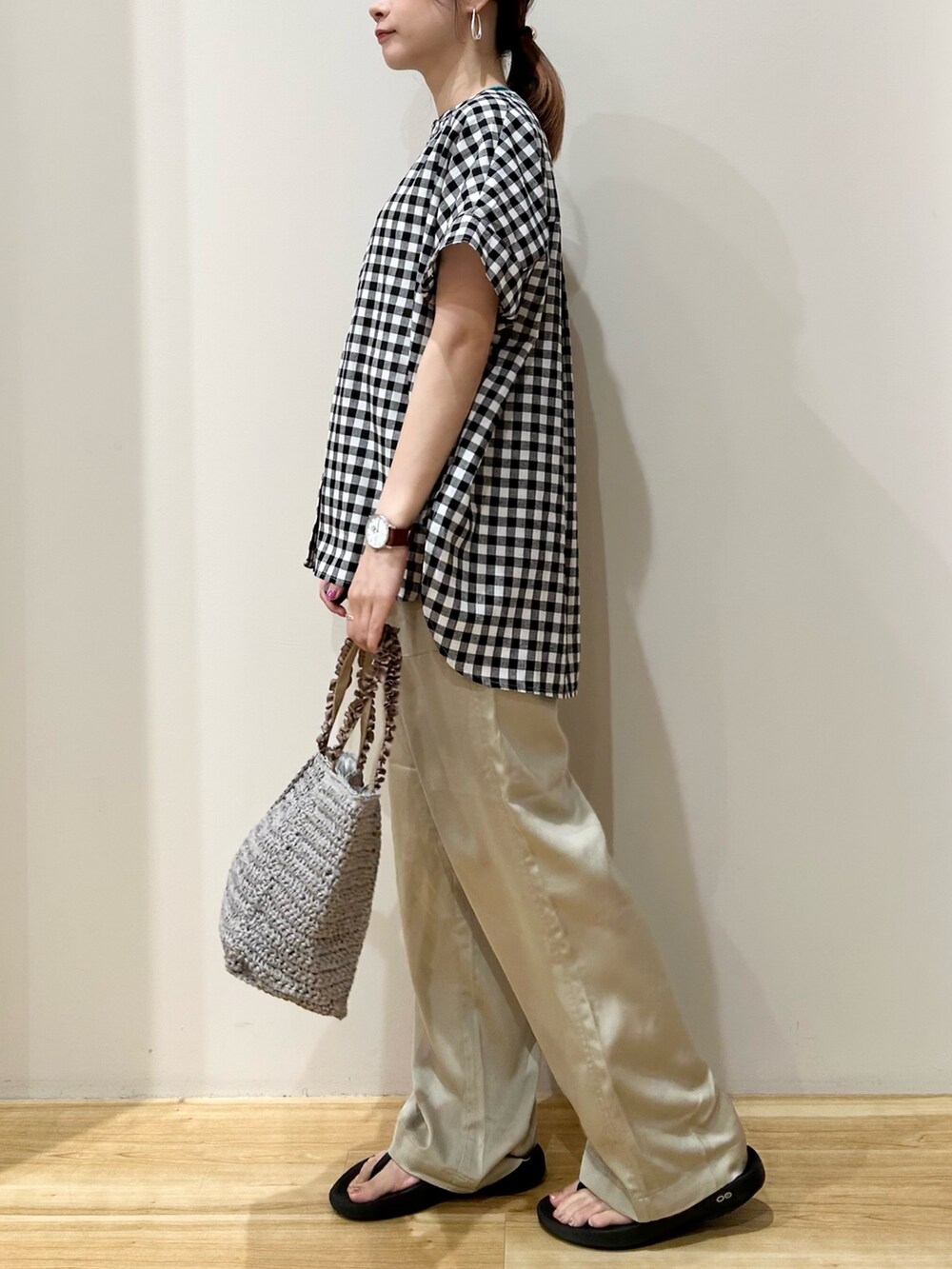 グレー系のかごバッグ、ブラック系のサンダル、ベージュ系のその他パンツを着用したレディースの夏コーディネートの2枚目の写真