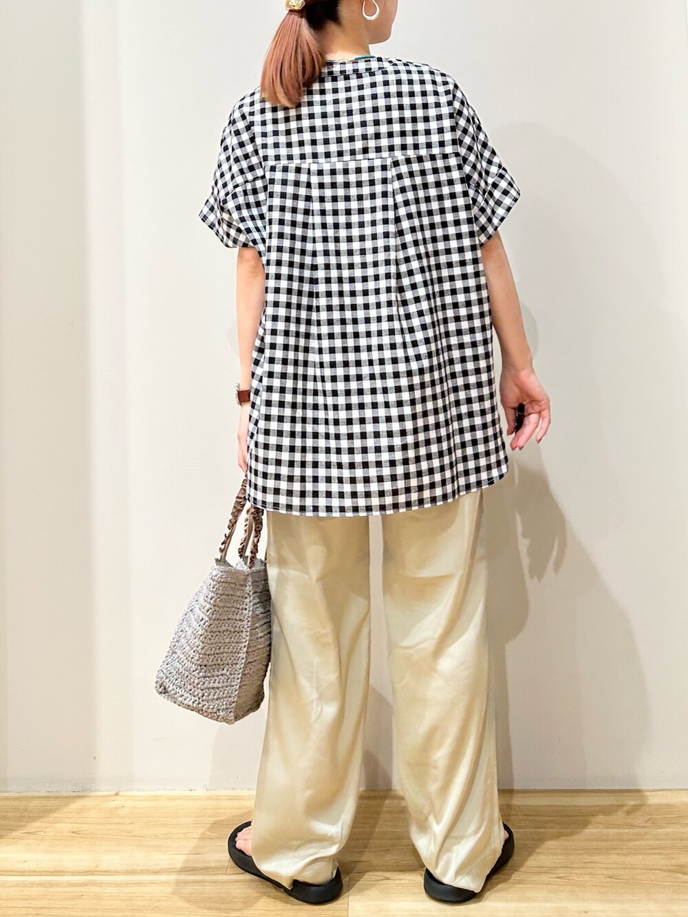 グレー系のかごバッグ、ブラック系のサンダル、ベージュ系のその他パンツを着用したレディースの夏コーディネートの3枚目の写真