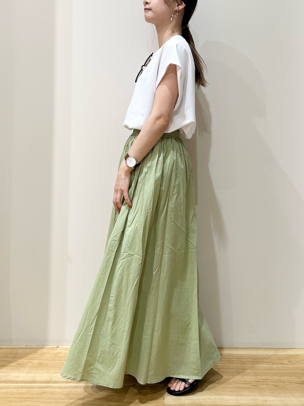 ホワイト系のTシャツ/カットソー、グリーン系のスカート、ブラック系のサンダルを着用したレディースの夏コーディネートの2枚目の写真