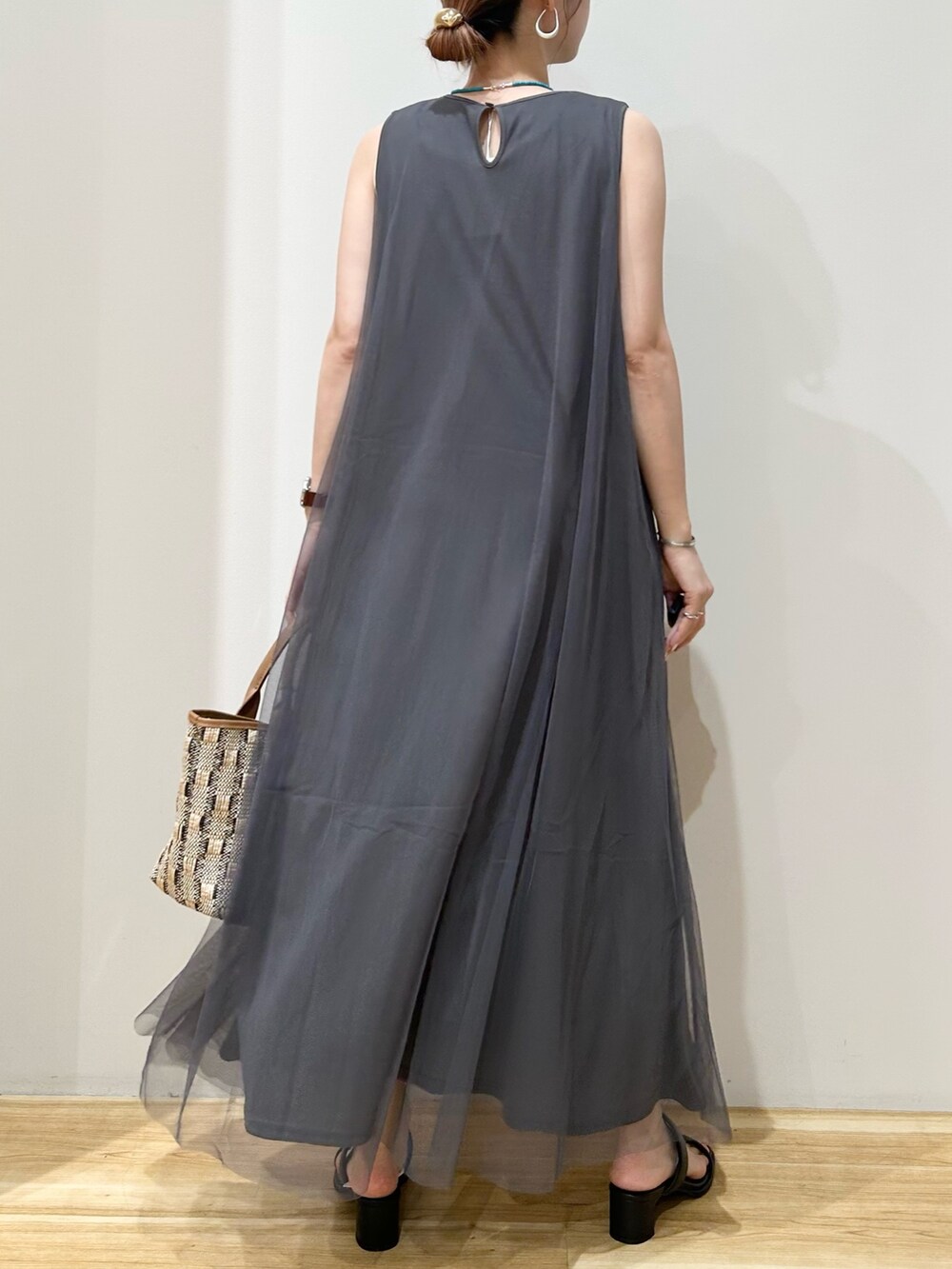 グレー系のワンピース、ベージュ系のバッグ、ブラック系のサンダルを着用したレディースの秋コーディネートの2枚目の写真