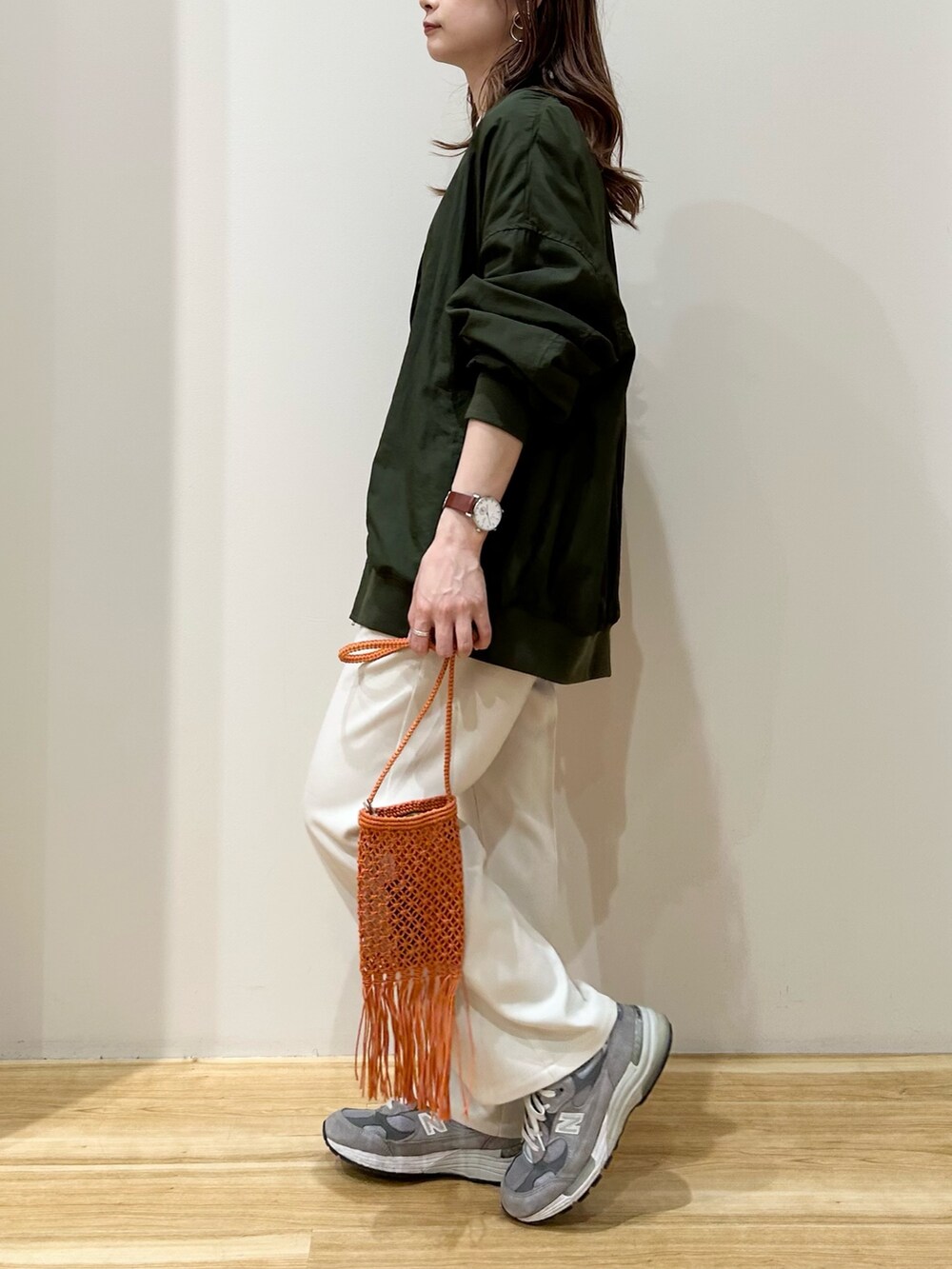 グリーン系のブルゾン、ホワイト系のニット/セーター、ホワイト系のスラックスを着用したレディースの春コーディネートの2枚目の写真