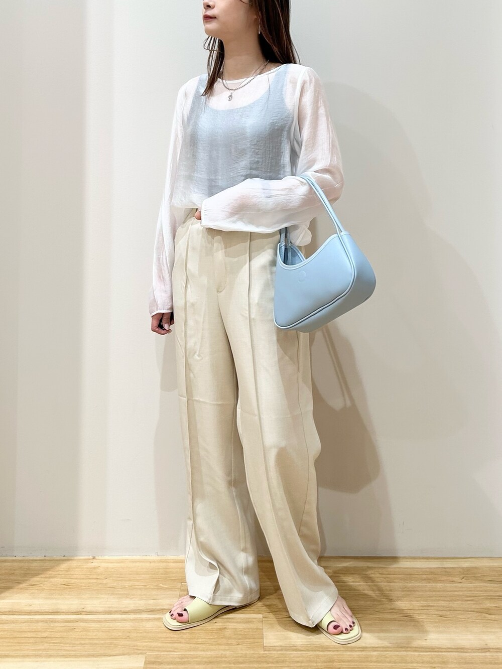 ブラウン系のテーラードジャケット、ブルー系のハンドバッグ、グリーン系のサンダルを着用したレディースの春コーディネートの4枚目の写真