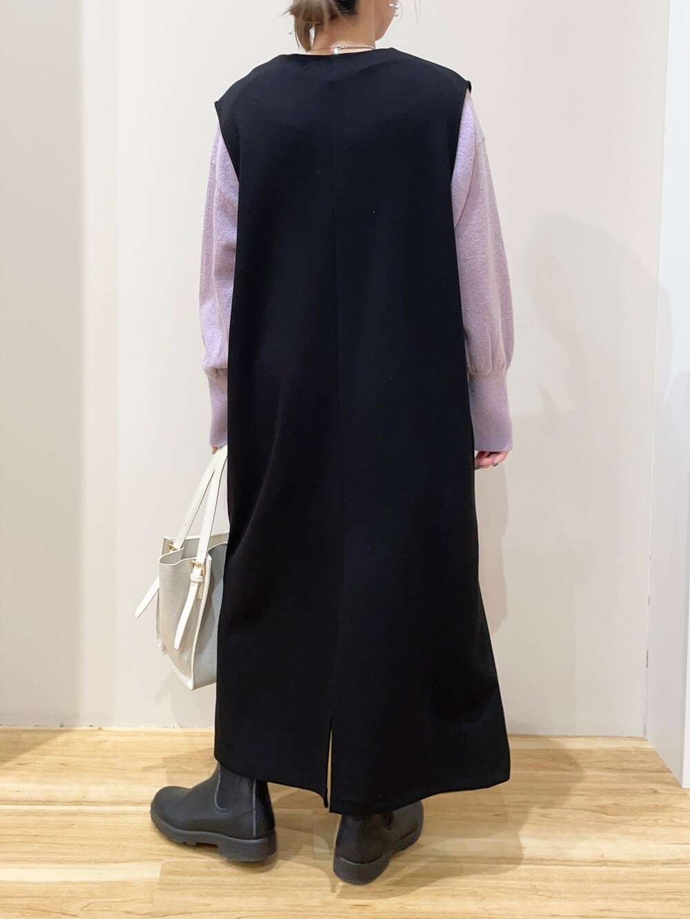 パープル系のニット/セーター、ブラック系のジャンパースカート、ホワイト系のトートバッグを着用したレディースの春コーディネートの3枚目の写真