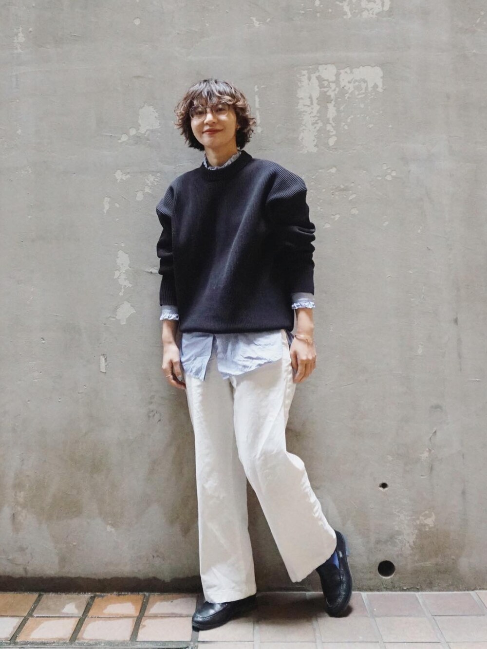 ブラック系のニット/セーター、ホワイト系のチノパンツ、ブラック系のローファーを着用したレディースの春コーディネートの3枚目の写真