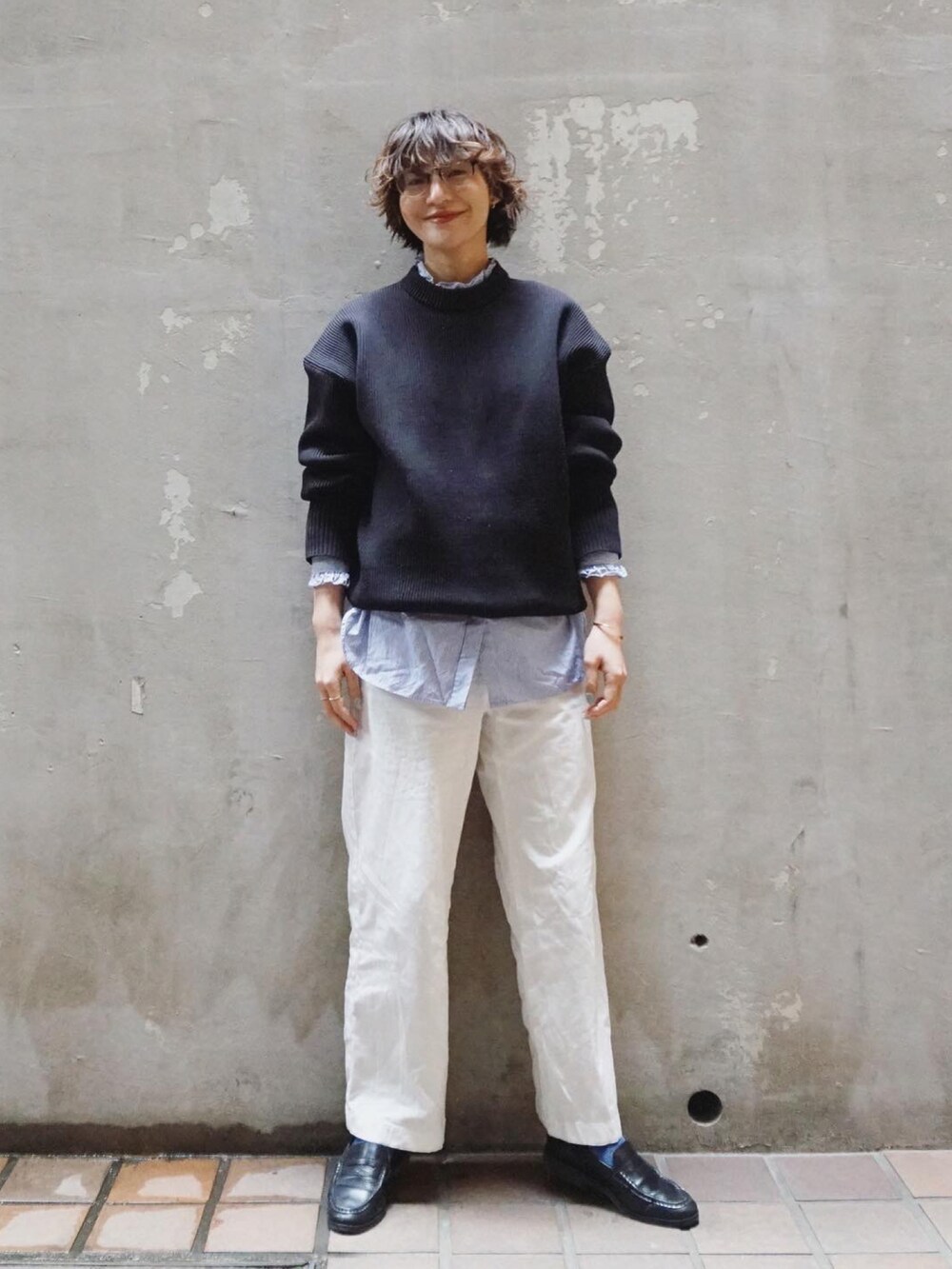 ブラック系のニット/セーター、ホワイト系のチノパンツ、ブラック系のローファーを着用したレディースの春コーディネートの2枚目の写真