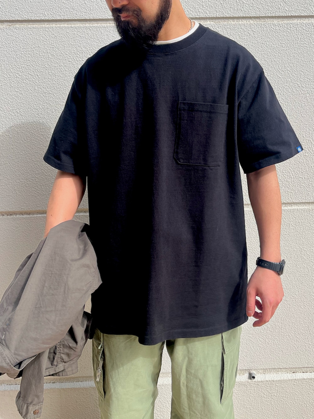 ブラック系のTシャツ/カットソー、グリーン系のカーゴパンツ、グリーン系のカバーオールを着用したメンズの春コーディネートの3枚目の写真