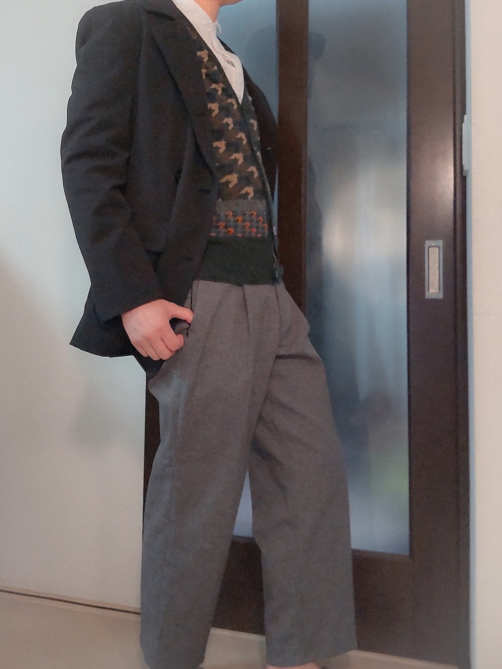 グリーン系のカーディガン/ボレロ、グレー系のスラックス、ブラック系のテーラードジャケットを着用したメンズの春コーディネートの2枚目の写真