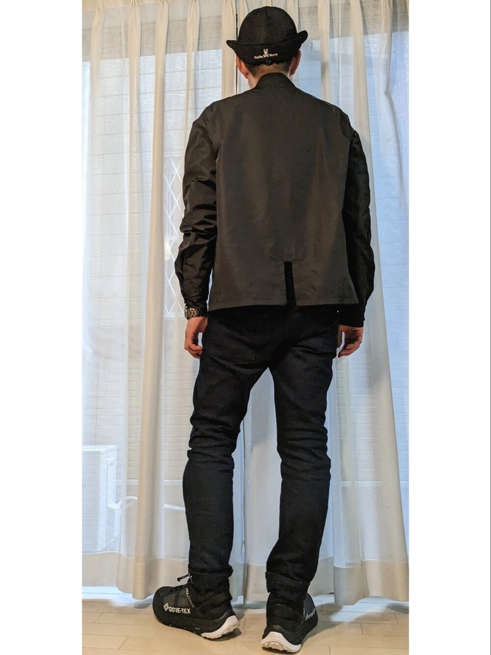 ブラック系のトップス、ブルー系のデニムパンツ、ブラック系のスニーカーを着用したメンズの春コーディネートの3枚目の写真