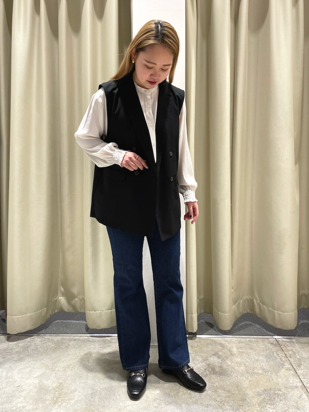 ブルー系のデニムパンツ、ブラック系のローファー、ブラック系のベストを着用したレディースの春コーディネートの2枚目の写真