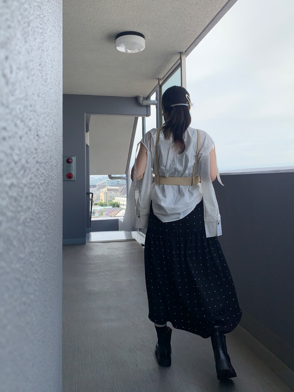 ブラック系のスカート、ホワイト系のシャツ/ブラウス、ブラック系のブーツを着用したレディースの夏コーディネートの2枚目の写真