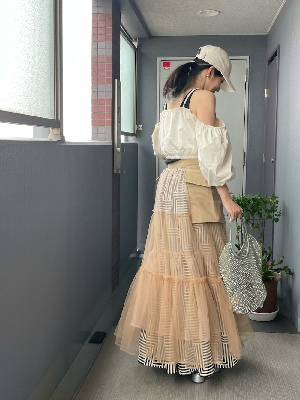 ホワイト系のベスト、パープル系のタンクトップ、ベージュ系のスカートを着用したレディースの秋コーディネートの2枚目の写真