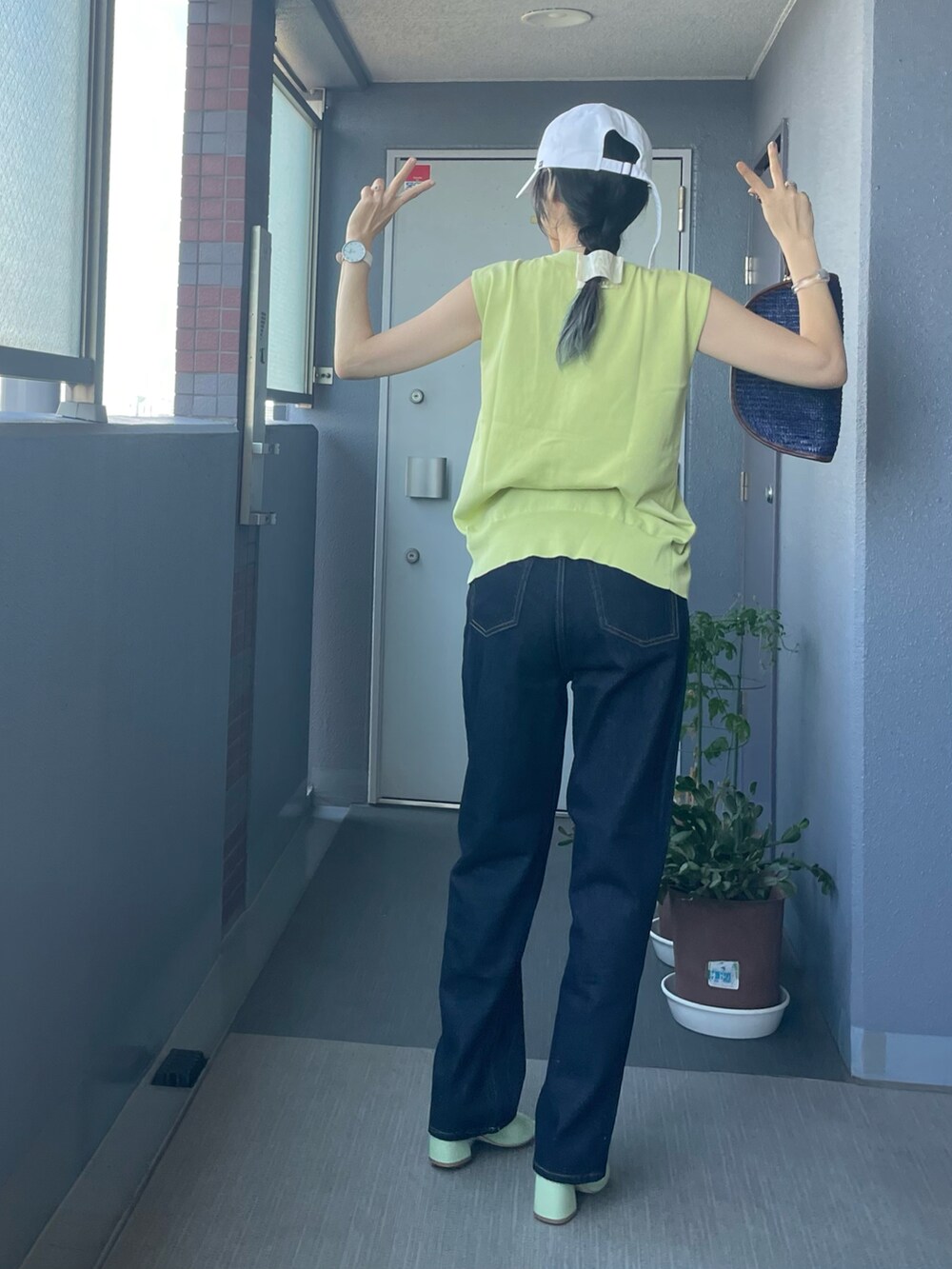 グリーン系のニット/セーター、ブルー系のデニムパンツ、ブルー系のクラッチバッグを着用したレディースの夏コーディネートの2枚目の写真