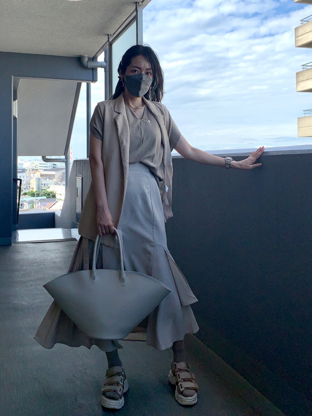 ベージュ系のベスト、ベージュ系のスカート、ベージュ系のサンダルを着用したレディースの夏コーディネートの2枚目の写真