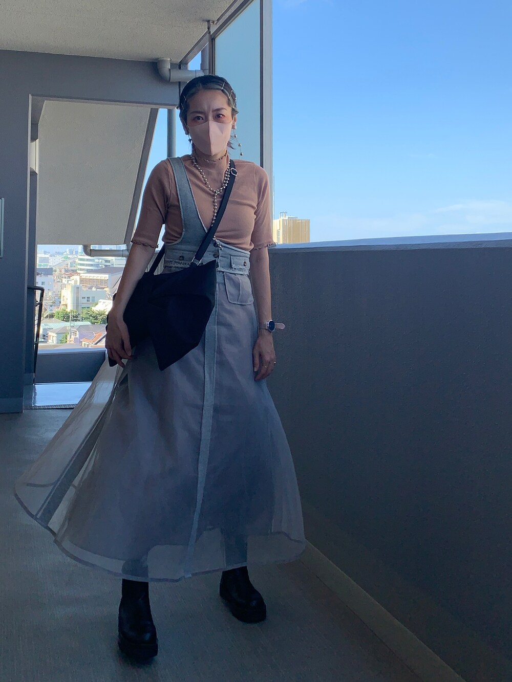 グレー系のスカート、ブラック系のブーツ、ピンク系のTシャツ/カットソーを着用したレディースの秋コーディネートの2枚目の写真