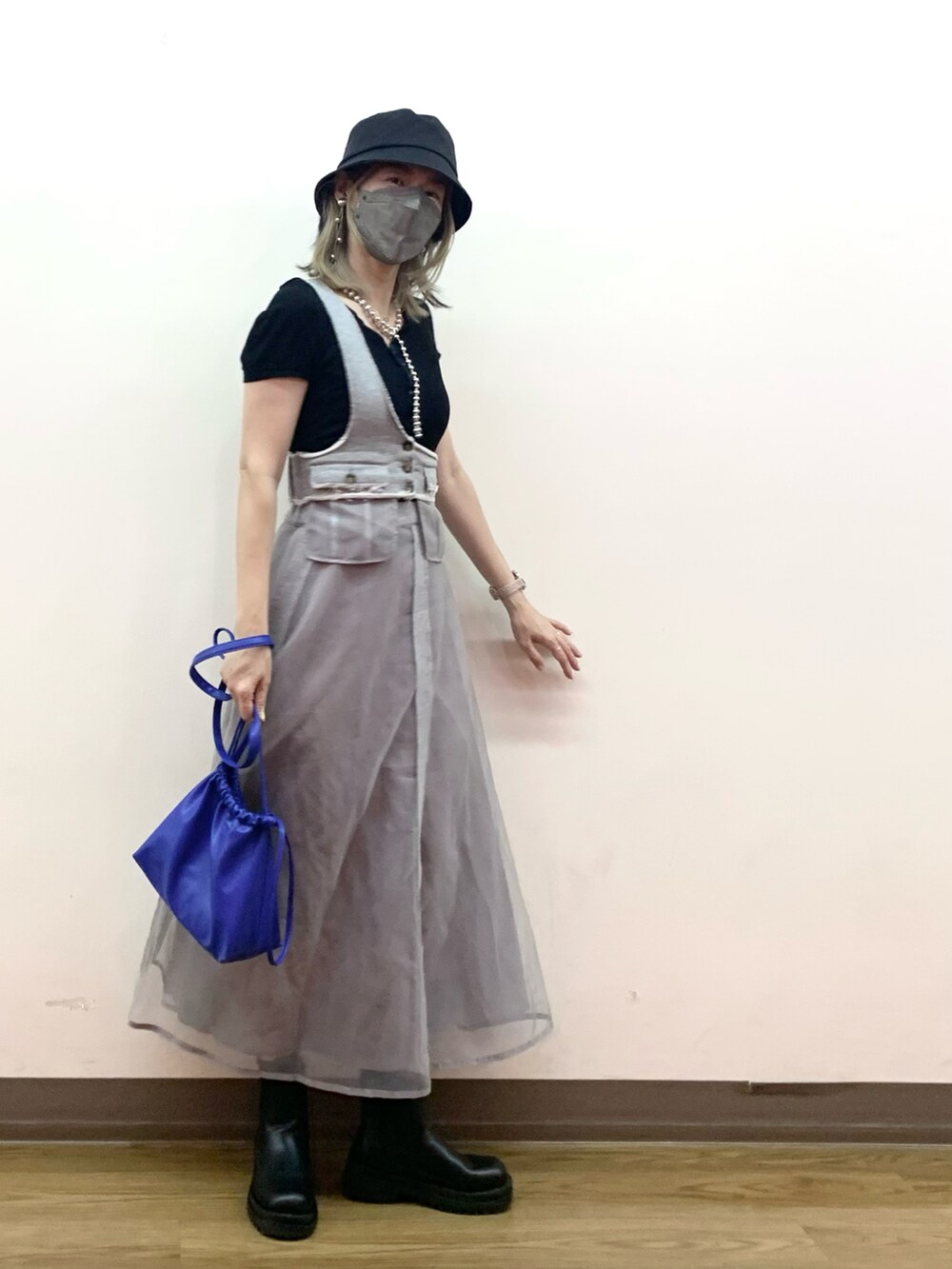 グレー系のスカート、ブラック系のブーツ、ブルー系のショルダーバッグを着用したレディースの秋コーディネートの2枚目の写真