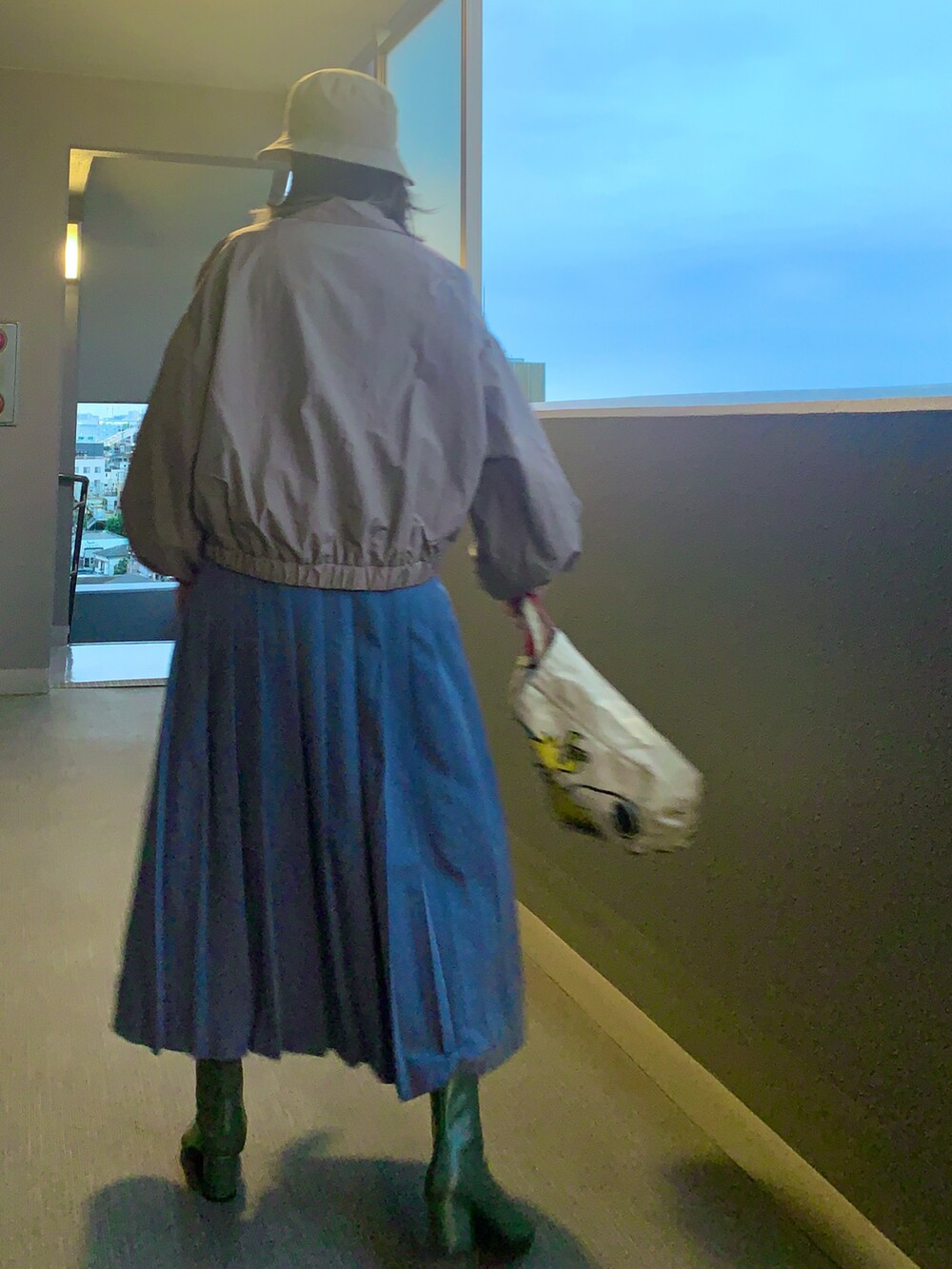 ベージュ系のナイロンジャケット、ブルー系のスカート、グリーン系のブーツを着用したレディースの秋コーディネートの2枚目の写真