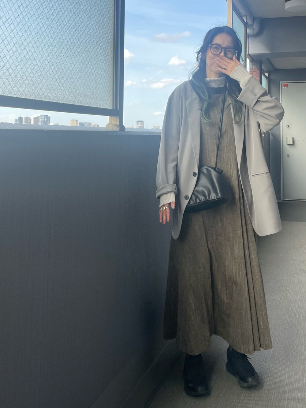 グレー系のテーラードジャケット、ブラウン系のワンピース、ブラック系のスニーカーを着用したレディースの春コーディネートの2枚目の写真