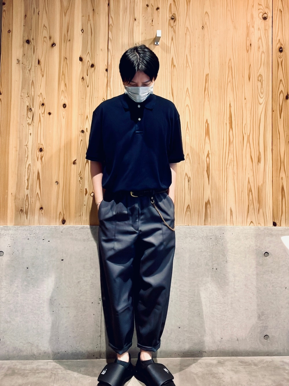 ブルー系のポロシャツ、グレー系のパンツ、ブラック系のスニーカーを着用したメンズの夏コーディネートの2枚目の写真