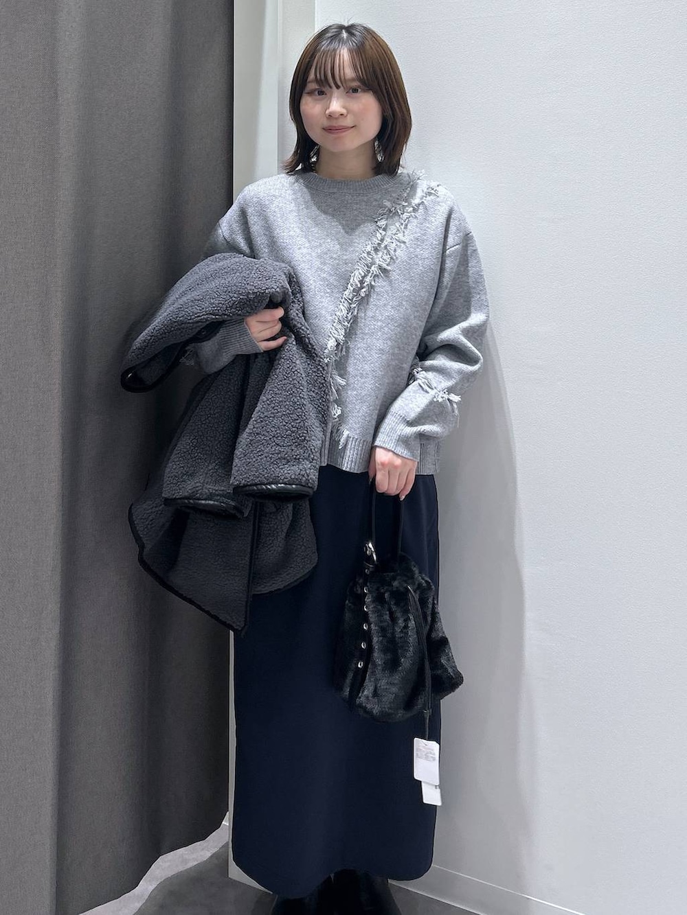 グレー系のブルゾン、ブラック系のハンドバッグ、ブラック系のブーツを着用したレディースの秋コーディネートの2枚目の写真