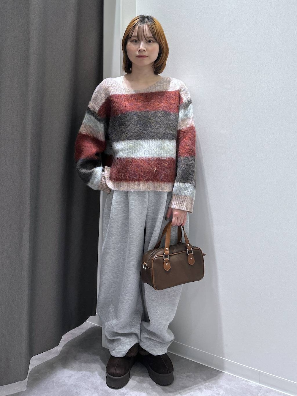 ブラウン系のスリッポン、グレー系のスウェットパンツ、ブラウン系のショルダーバッグを着用したレディースの秋コーディネートの2枚目の写真