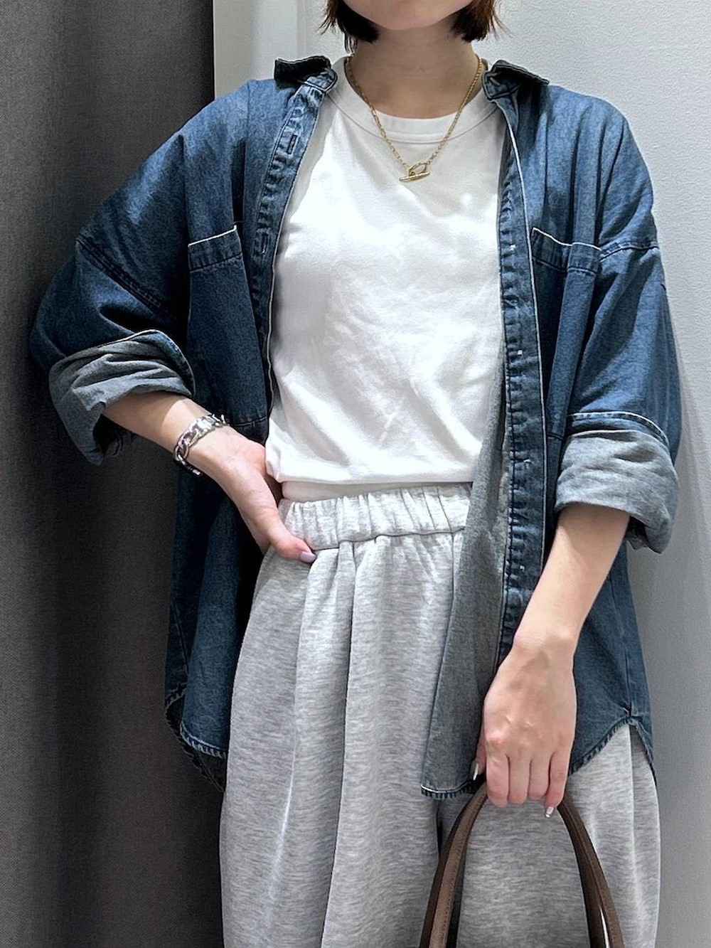 ブルー系のシャツ/ブラウス、ホワイト系のスニーカー、ブラウン系のボストンバッグを着用したレディースの秋コーディネートの3枚目の写真