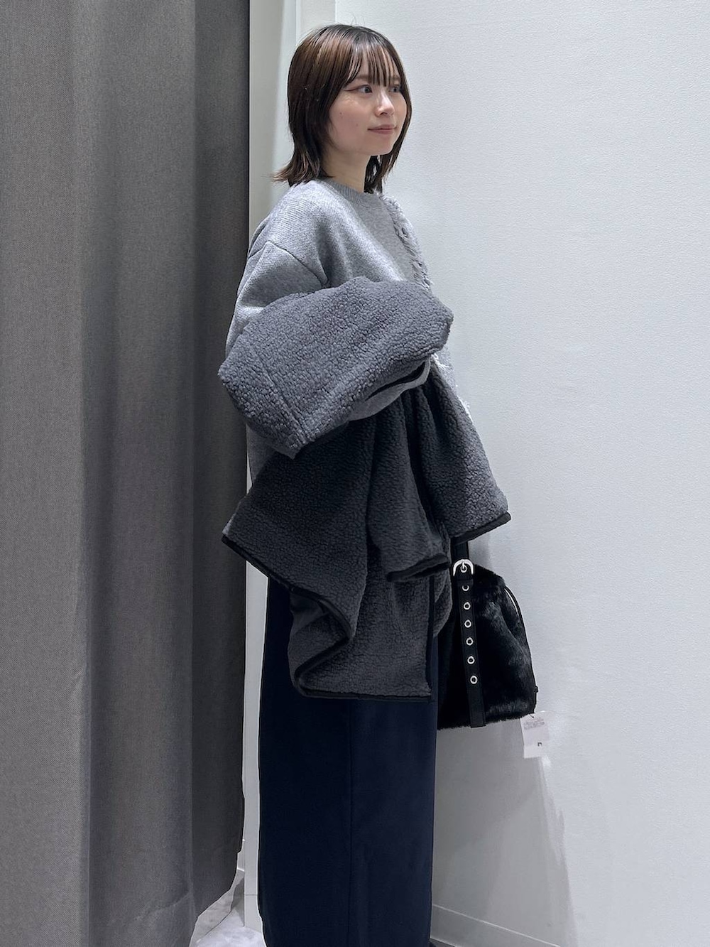 グレー系のブルゾン、ブラック系のハンドバッグ、ブラック系のブーツを着用したレディースの秋コーディネートの3枚目の写真