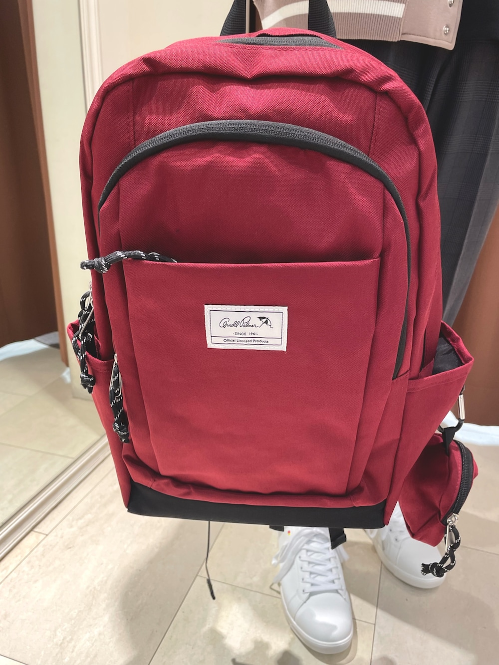 ブルー系のスニーカー、レッド系のバックパック/リュック、ベージュ系のスタジャンを着用したメンズの秋コーディネートの4枚目の写真