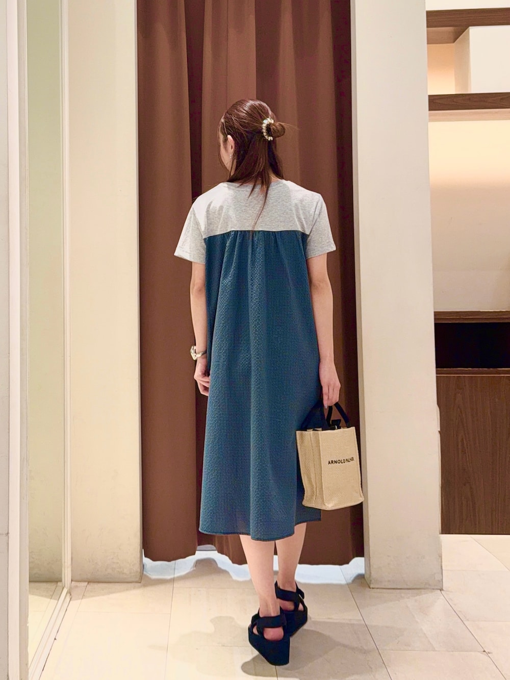 グレー系のワンピース、ベージュ系のトートバッグ、ブラック系のサンダルを着用したレディースの夏コーディネートの3枚目の写真