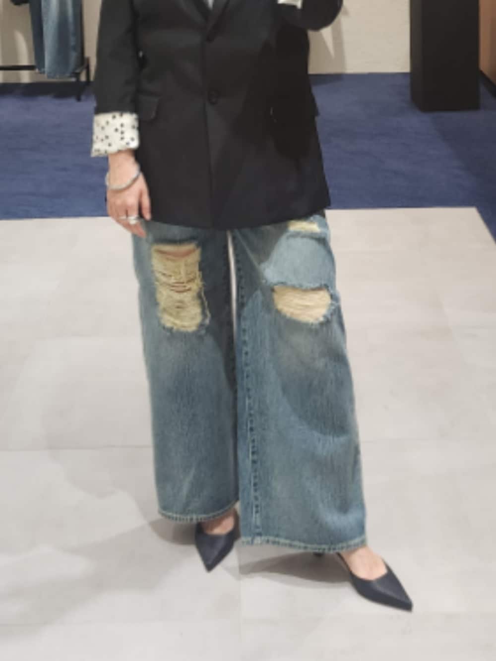 ブラック系のテーラードジャケット、ブルー系のデニムパンツ、ブラック系のパンプスを着用したレディースの秋コーディネートの3枚目の写真