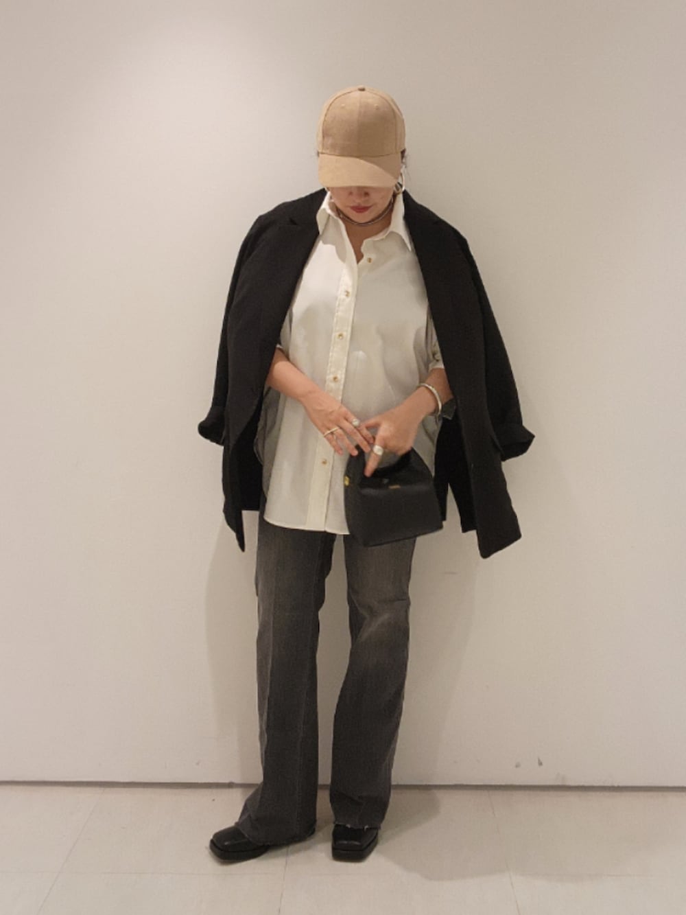 ブラック系のベスト、ホワイト系のシャツ/ブラウス、ブラック系のデニムパンツを着用したレディースの秋コーディネートの2枚目の写真