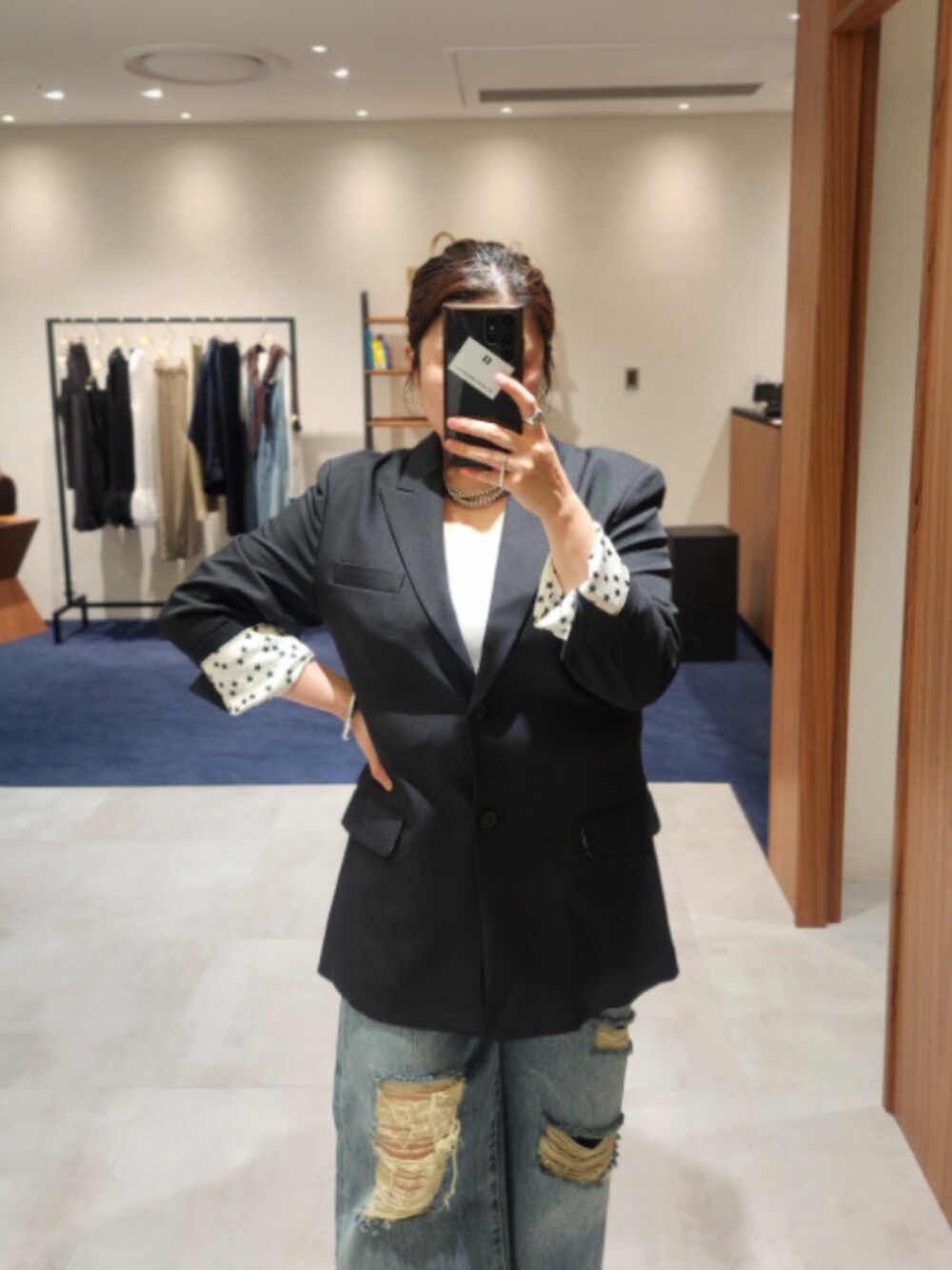 ブラック系のテーラードジャケット、ブルー系のデニムパンツ、ブラック系のパンプスを着用したレディースの秋コーディネートの2枚目の写真