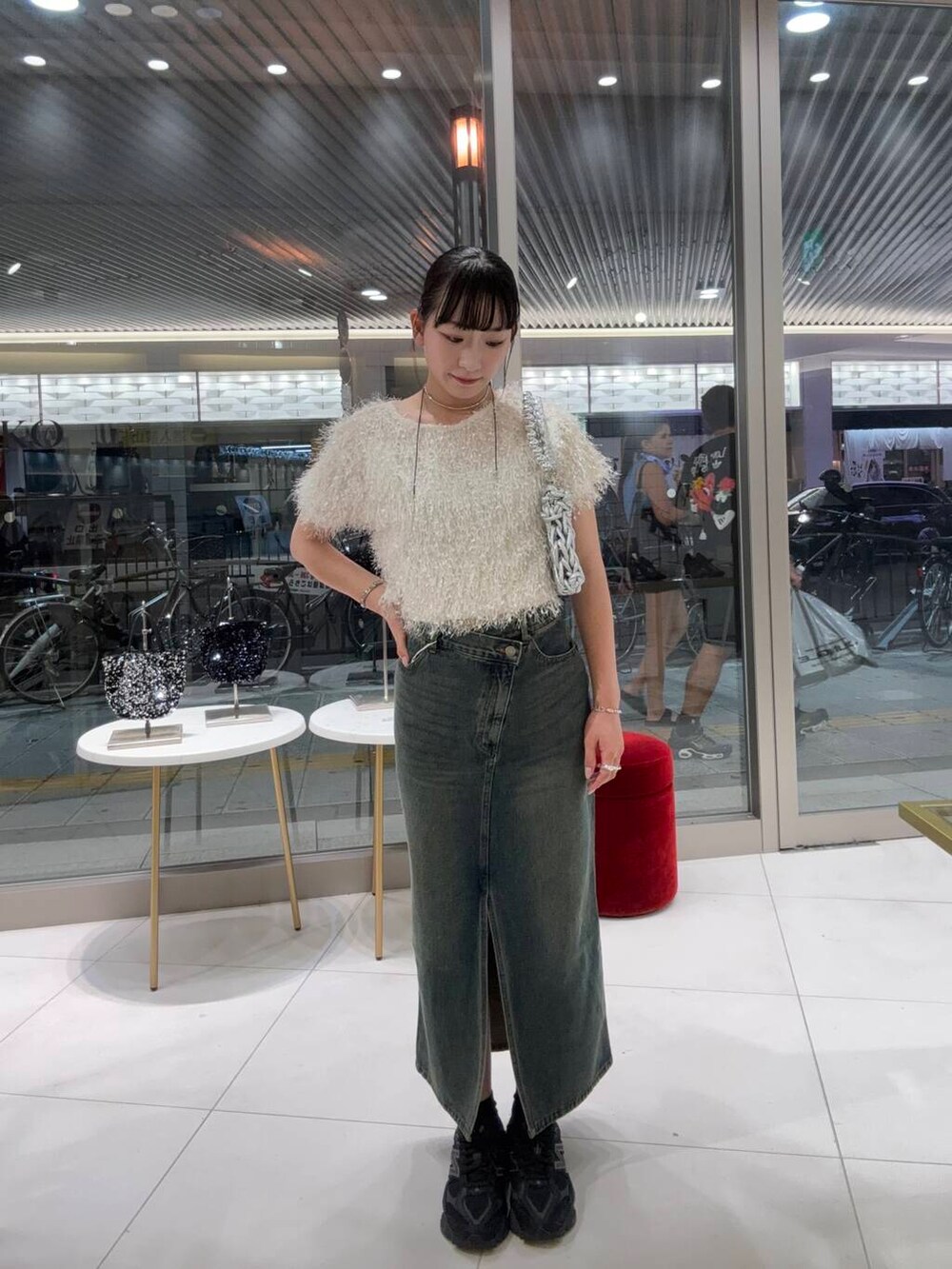 シルバー系のハンドバッグ、ホワイト系のTシャツ/カットソー、ブラウン系のスカートを着用したレディースの夏コーディネートの2枚目の写真