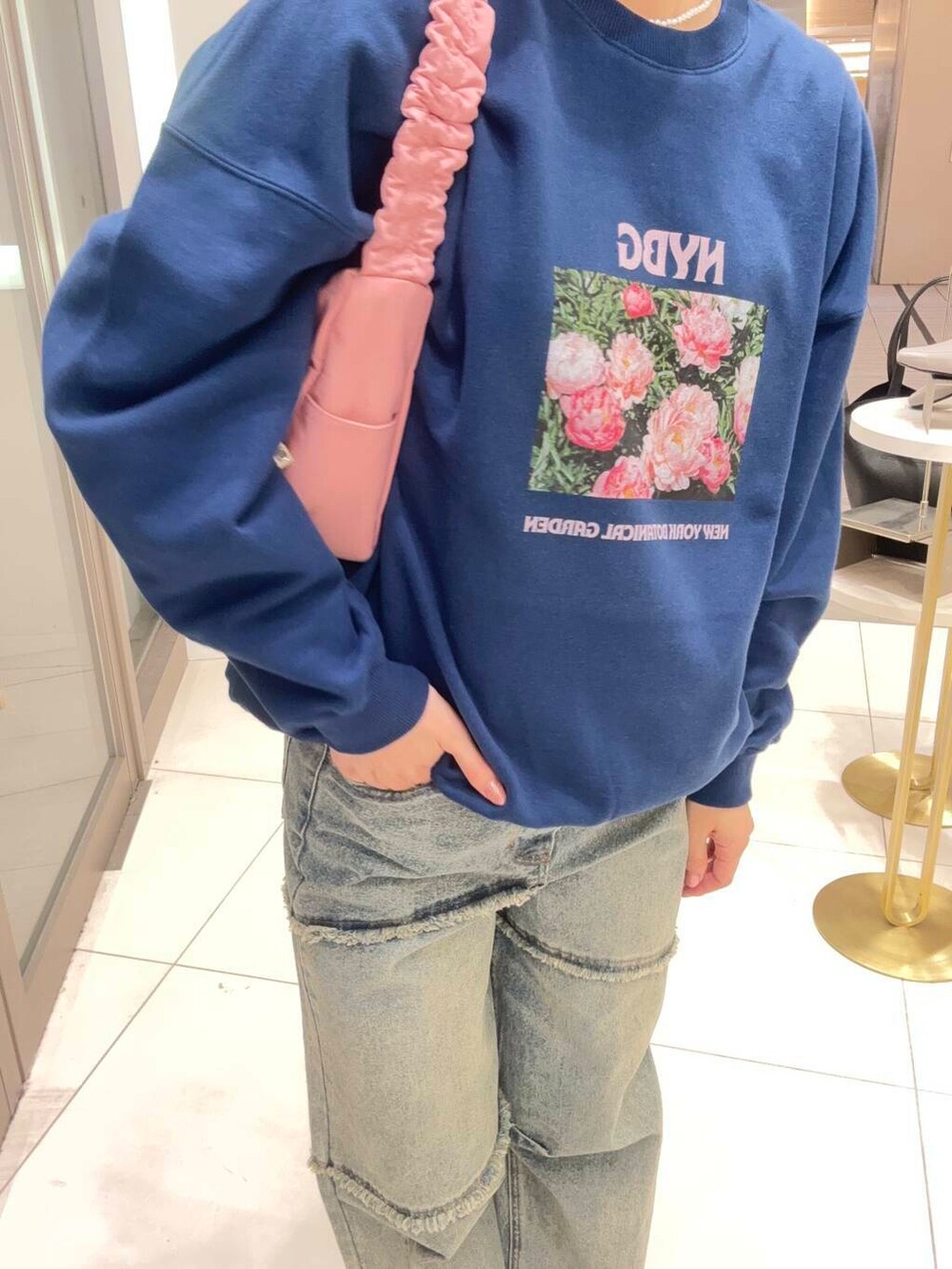レッド系のショルダーバッグ、ブルー系のデニムパンツ、ブルー系のスウェットを着用したレディースの春コーディネートの2枚目の写真