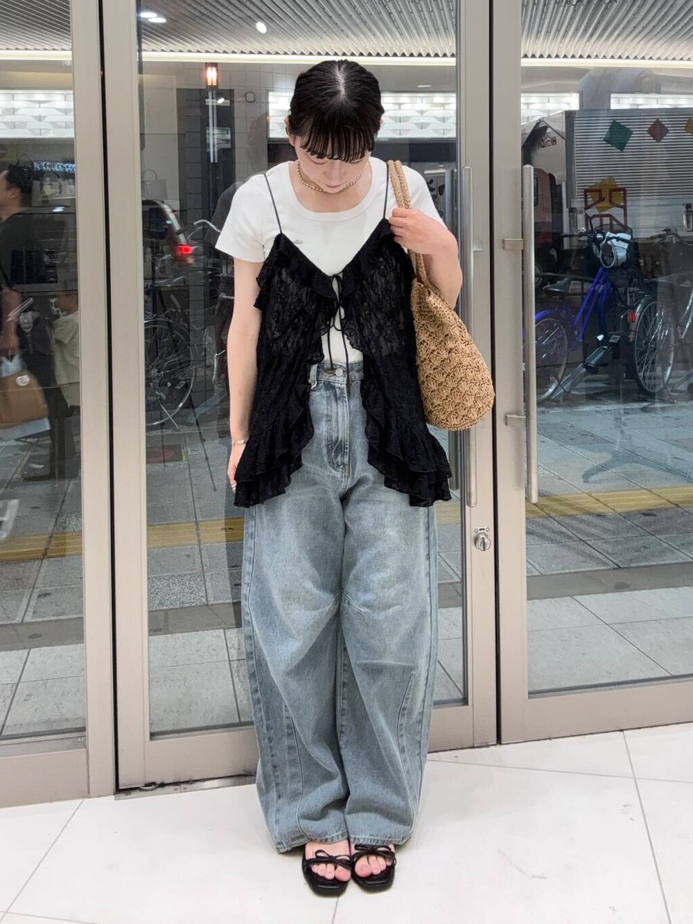 ベージュ系のトートバッグ、ブルー系のデニムパンツ、ホワイト系のTシャツ/カットソーを着用したレディースの夏コーディネートの2枚目の写真