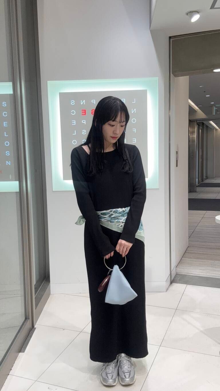 ブルー系のハンドバッグ、ブラック系のワンピースを着用したレディースの冬コーディネートの2枚目の写真