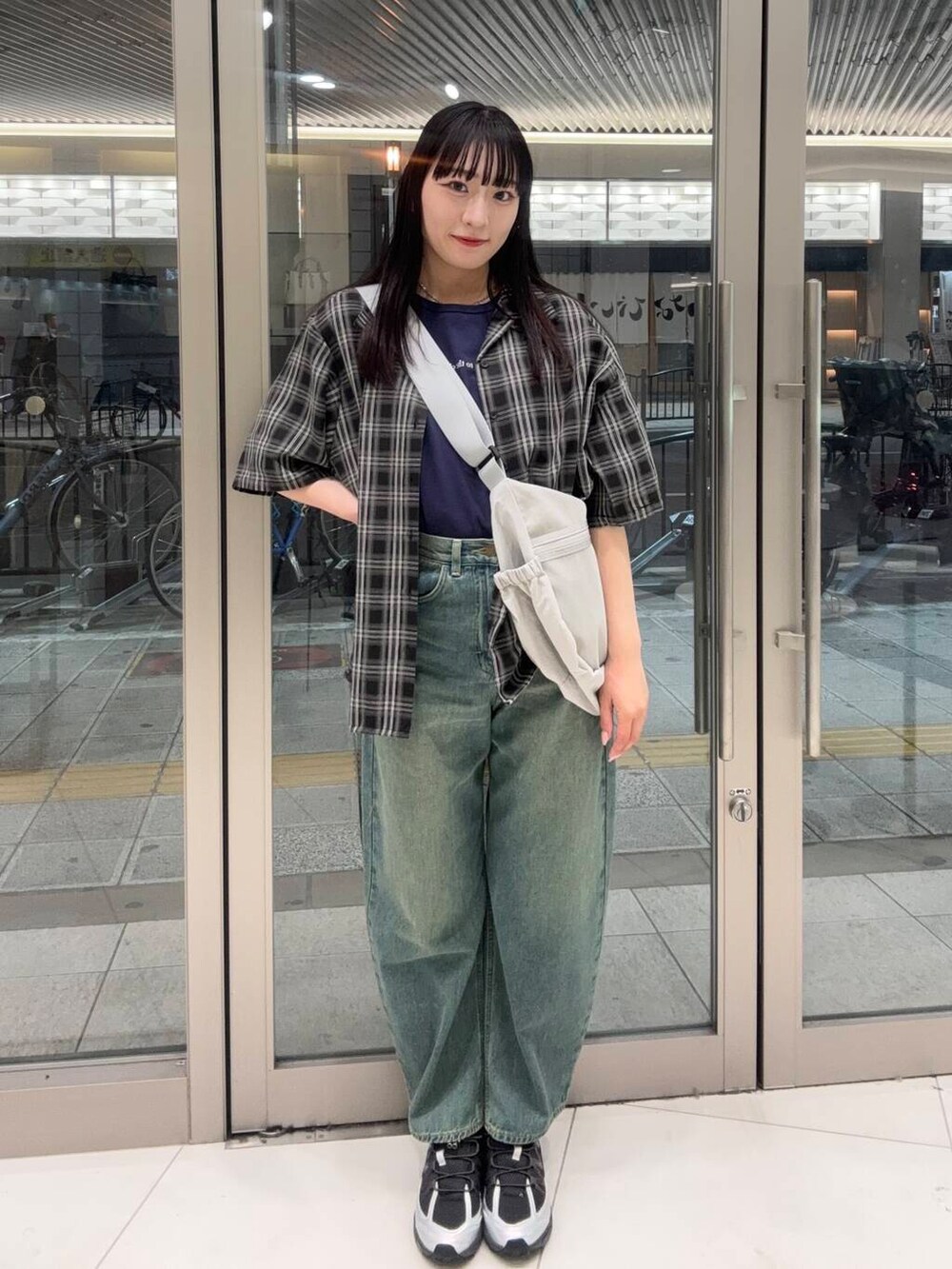 グリーン系のデニムパンツ、グレー系のスニーカー、ベージュ系のショルダーバッグを着用したレディースの春コーディネートの2枚目の写真