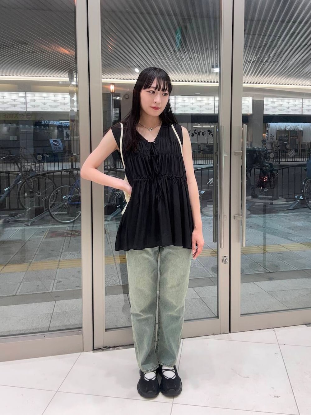 ブラック系のスニーカー、ブルー系のデニムパンツ、ホワイト系のショルダーバッグを着用したレディースの春コーディネートの2枚目の写真