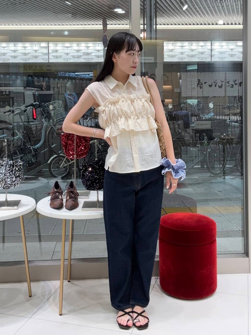 ブルー系のデニムパンツ、ベージュ系のトートバッグ、ブラック系のサンダルを着用したレディースの夏コーディネートの2枚目の写真