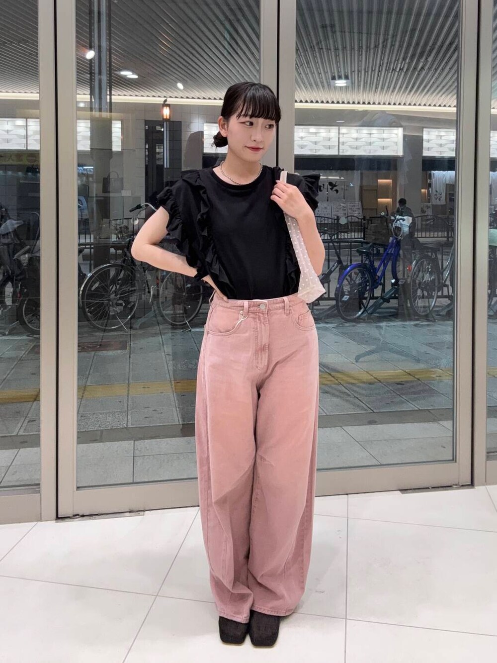 ブラック系のパンプス、ピンク系のデニムパンツ、ベージュ系のハンドバッグを着用したレディースの夏コーディネートの2枚目の写真