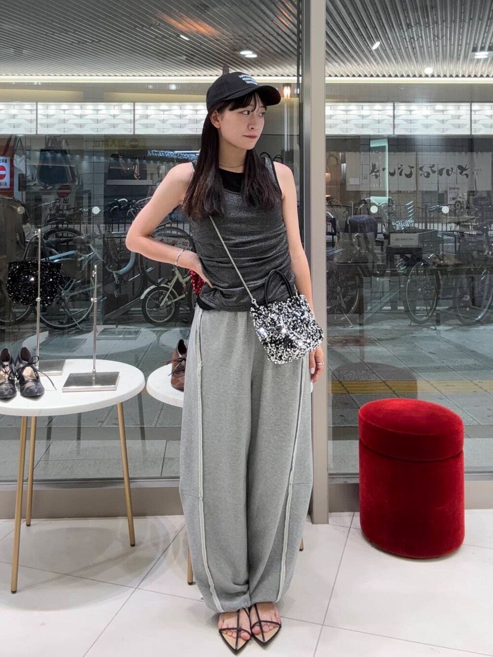 シルバー系のショルダーバッグ、ブラック系のサンダル、グレー系のスウェットパンツを着用したレディースの夏コーディネートの2枚目の写真